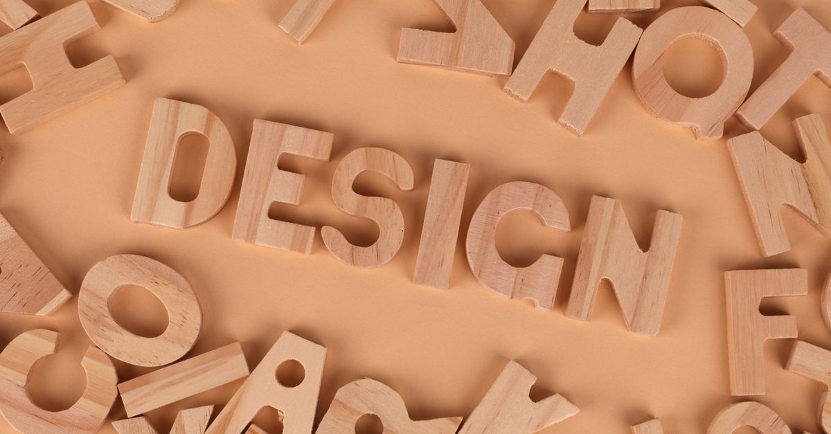Wooden letters arranged to form the word 'design' on a brown background, top view.